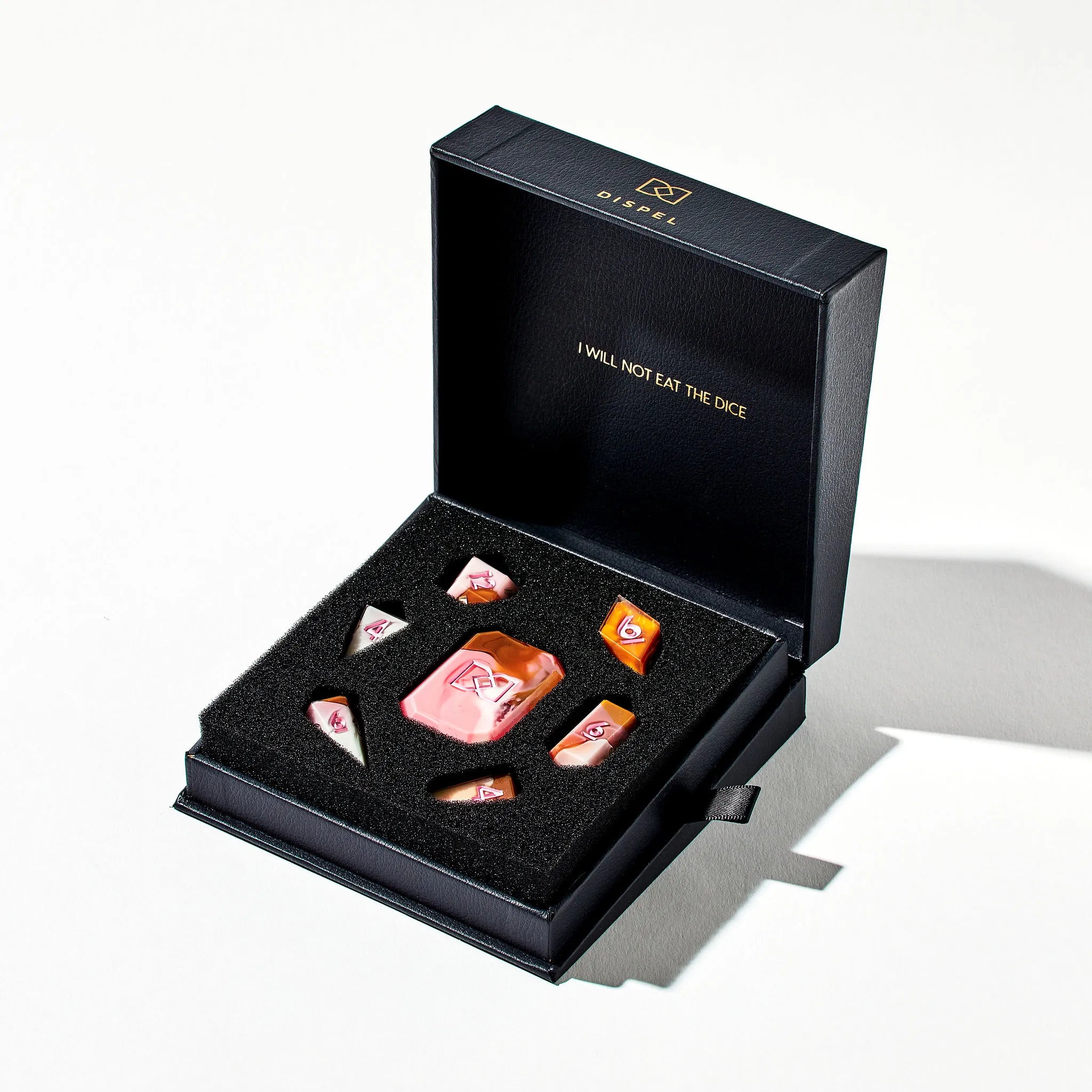 A Brown Pink and White Colored Jewel-Shaped Dice Set on a White Background in the Packaging