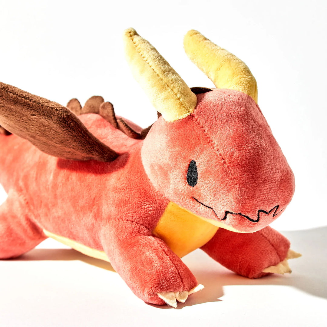 A close up of a plush red dragon on a White Background