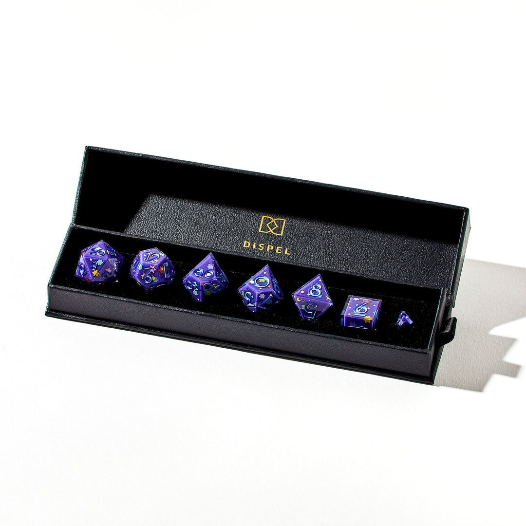 Close up of a purple dice set with light blue inked numbers and Konpeitō stickers on each face inside the packaging