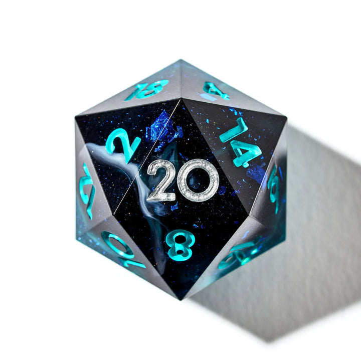 Close up of a blue and black D20 with teal and silver numbers