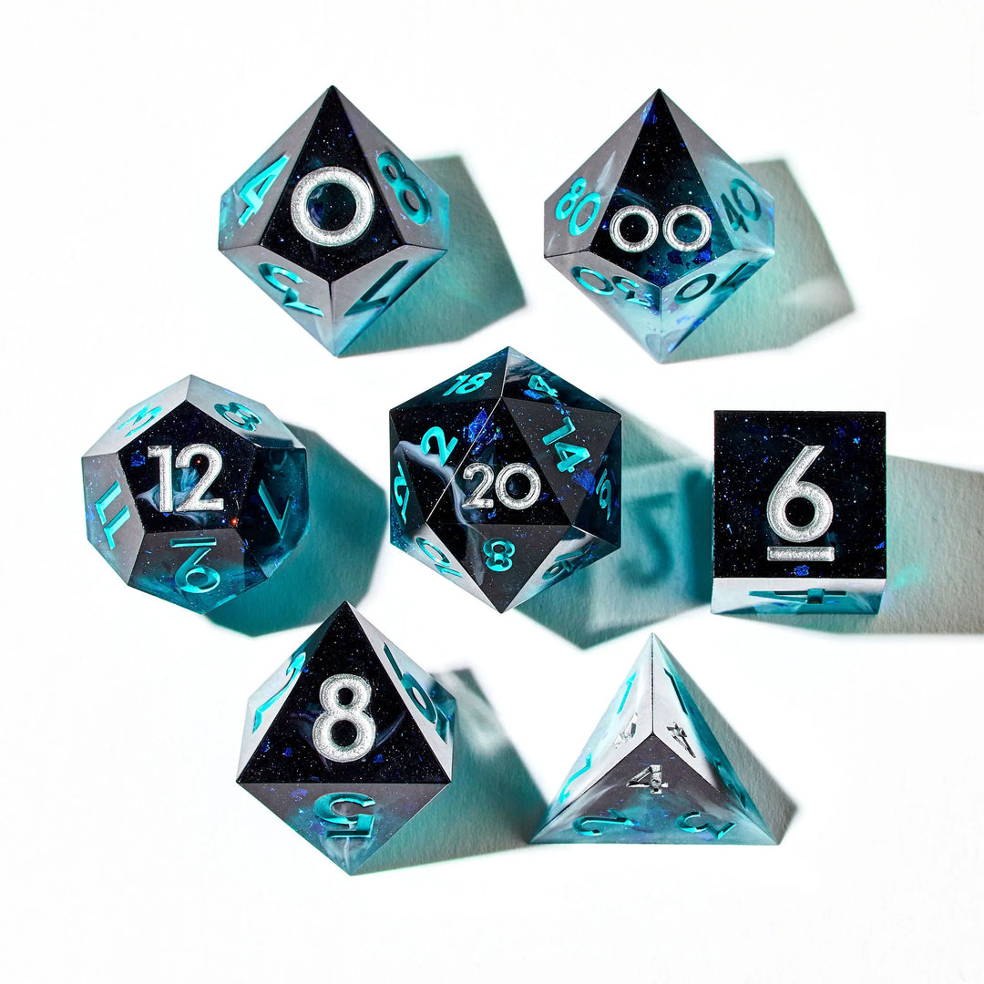 Close up of a black and blue 7 piece dice set with teal and silver colors