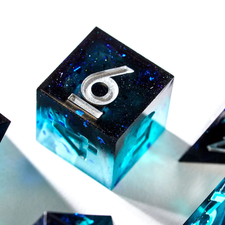 Close up of a black and blue D6 with teal and silver numbers