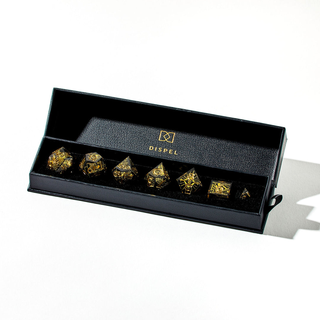 Close up of a black and gold dice set with wing and sun designs in its packaging